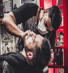 Imagem do barbeiro fazendo a barba tradicional com a navalha